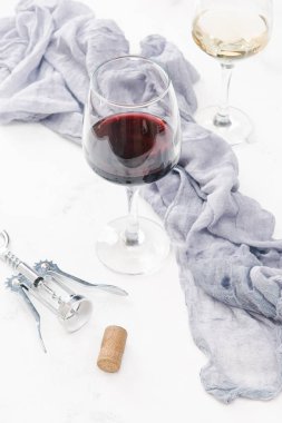 Kırmızı ve beyaz şarap cork, tirbuşon ve keten bezi ile beyaz beton yüzeyinde bardak