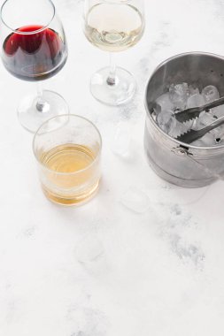 Kırmızı ve beyaz şarap, viski ve pot beyaz beton zemin üzerine buz küpleri ile cam gözlükler