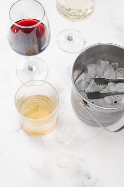 Kırmızı ve beyaz şarap, viski ve pot beyaz beton zemin üzerine buz küpleri ile cam gözlükler