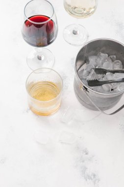 Kırmızı ve beyaz şarap, viski ve pot beyaz beton zemin üzerine buz küpleri ile cam gözlükler