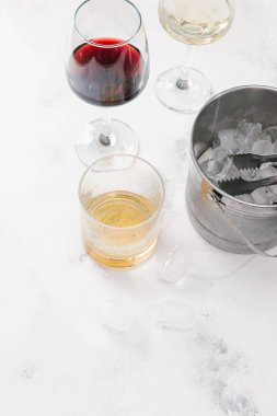 Kırmızı ve beyaz şarap, viski ve pot beyaz beton zemin üzerine buz küpleri ile cam gözlükler
