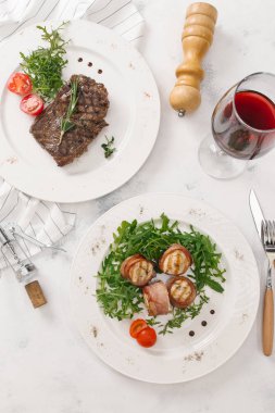 Biftek ve pastırma üstten görünüm Beyaz tabaklar roka ve biberiye dal ile hizmet alır