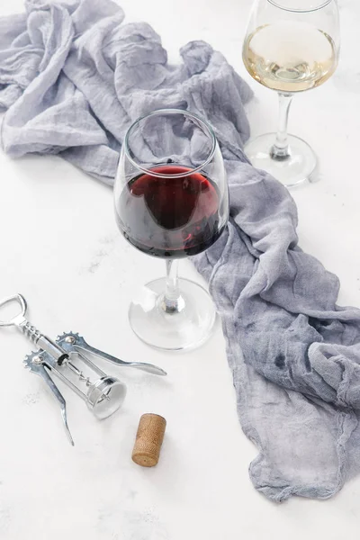 Kırmızı ve beyaz şarap cork, tirbuşon ve keten bezi ile beyaz beton yüzeyinde bardak