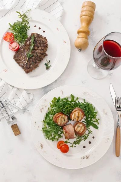 Biftek ve pastırma üstten görünüm Beyaz tabaklar roka ve biberiye dal ile hizmet alır