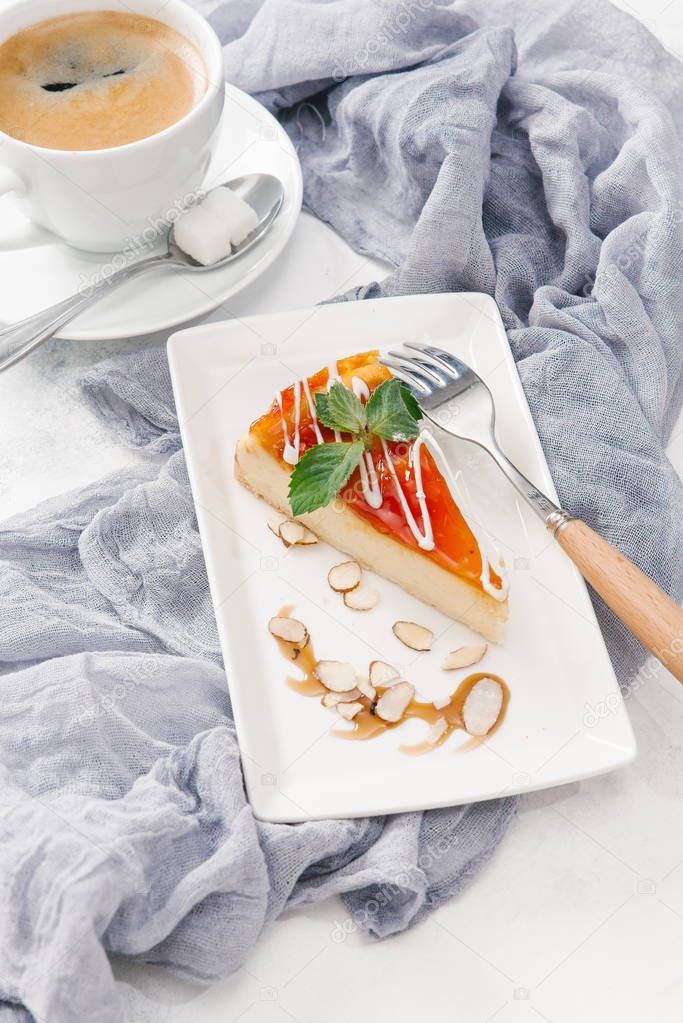Fresh cheesecake on white plate with mint leaves served with coffee