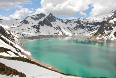 Bulutlu gökyüzü altında karlı dağlarda turkuaz Gölü manzaralı görünüm