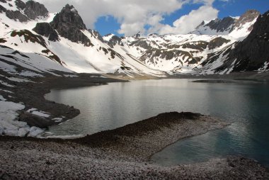 Bulutlu gökyüzü altında karlı dağlarda turkuaz Gölü manzaralı görünüm