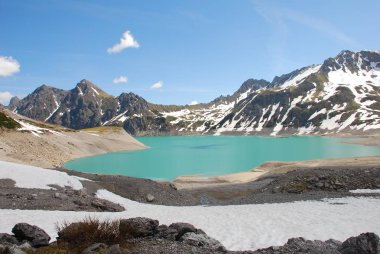 Bulutlu gökyüzü altında karlı dağlarda turkuaz Gölü manzaralı görünüm
