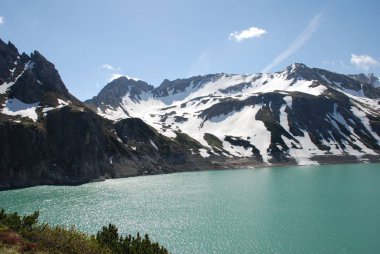 Bulutlu gökyüzü altında karlı dağlarda turkuaz Gölü manzaralı görünüm