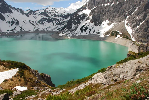 Bulutlu gökyüzü altında karlı dağlarda turkuaz Gölü manzaralı görünüm