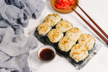 Beyaz taş zemin üzerine zencefil ile sunulan geleneksel pişmiş Japon Suşi rulo