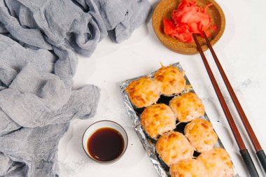 Beyaz taş zemin üzerine zencefil ile sunulan geleneksel pişmiş Japon Suşi rulo