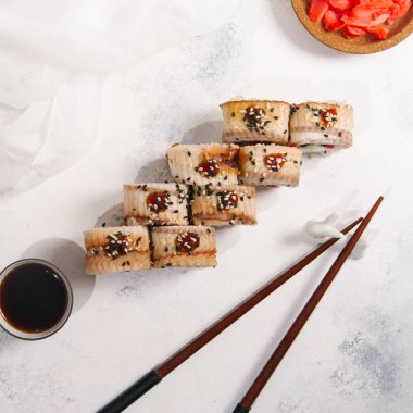 Geleneksel Japon siyah susam yemek çubukları, soya sosu ve zencefil ile açık gri taş renkli rulo