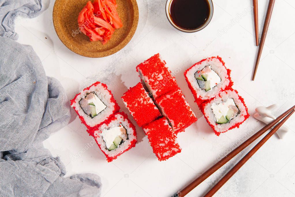 Top view of traditional japanese sushi rolls served with ginger on white stone background