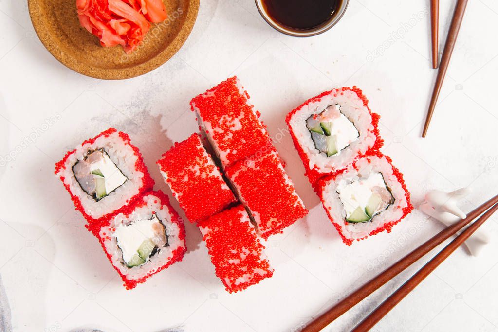 Top view of traditional japanese sushi rolls served with ginger on white stone background