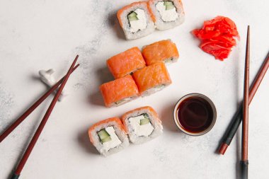 Zencefil, soya sosu ve yemek çubukları ile taş zemin üzerine taze suşi rulo
