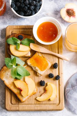 Tost kayısı reçelli ekmek ve beyaz ahşap masa yapraklarda ile taze meyve. Lezzetli kahvaltı.