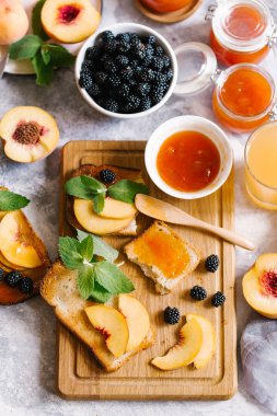 Tost kayısı reçelli ekmek ve beyaz ahşap masa yapraklarda ile taze meyve. Lezzetli kahvaltı.