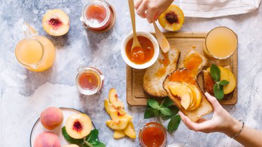 Tost kayısı reçelli ekmek ve beyaz ahşap masa yapraklarda ile taze meyve. Lezzetli kahvaltı.