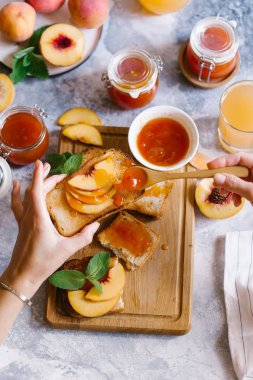 Tost kayısı reçelli ekmek ve beyaz ahşap masa yapraklarda ile taze meyve. Lezzetli kahvaltı.