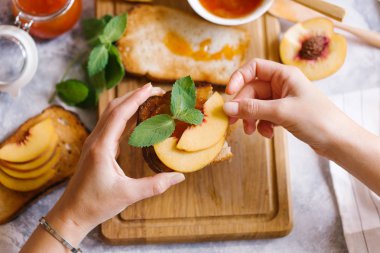 Tost kayısı reçelli ekmek ve beyaz ahşap masa yapraklarda ile taze meyve. Lezzetli kahvaltı.