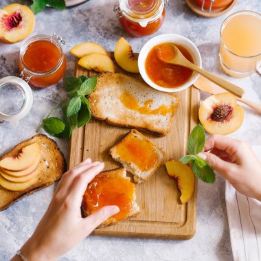 Tost kayısı reçelli ekmek ve beyaz ahşap masa yapraklarda ile taze meyve. Lezzetli kahvaltı.