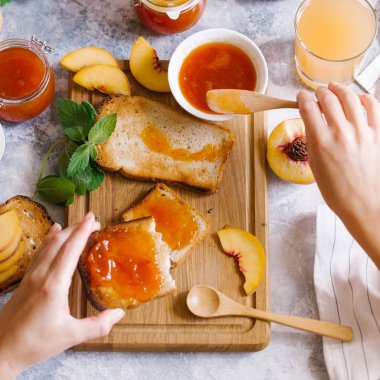 Tost kayısı reçelli ekmek ve beyaz ahşap masa yapraklarda ile taze meyve. Lezzetli kahvaltı.