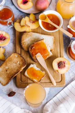 Tost kayısı reçelli ekmek ve beyaz ahşap masa yapraklarda ile taze meyve. Lezzetli kahvaltı.