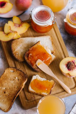 Tost kayısı reçelli ekmek ve beyaz ahşap masa yapraklarda ile taze meyve. Lezzetli kahvaltı.