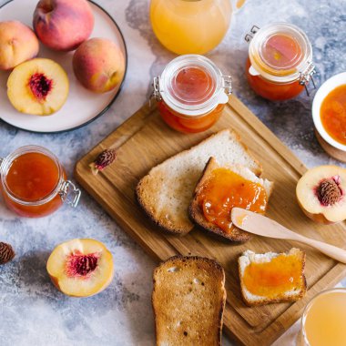 Tost kayısı reçelli ekmek ve beyaz ahşap masa yapraklarda ile taze meyve. Lezzetli kahvaltı.