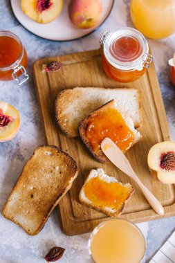 Tost kayısı reçelli ekmek ve beyaz ahşap masa yapraklarda ile taze meyve. Lezzetli kahvaltı.