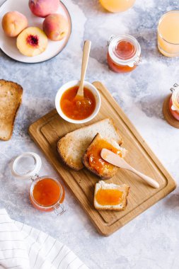 Tost kayısı reçelli ekmek ve beyaz ahşap masa yapraklarda ile taze meyve. Lezzetli kahvaltı.