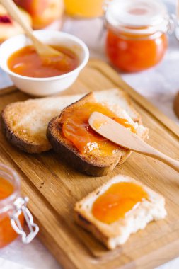 Tost kayısı reçelli ekmek ve beyaz ahşap masa yapraklarda ile taze meyve. Lezzetli kahvaltı.