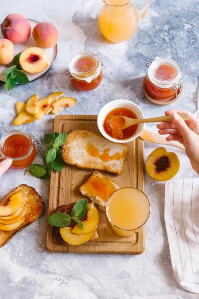 Tost kayısı reçelli ekmek ve beyaz ahşap masa yapraklarda ile taze meyve. Lezzetli kahvaltı.