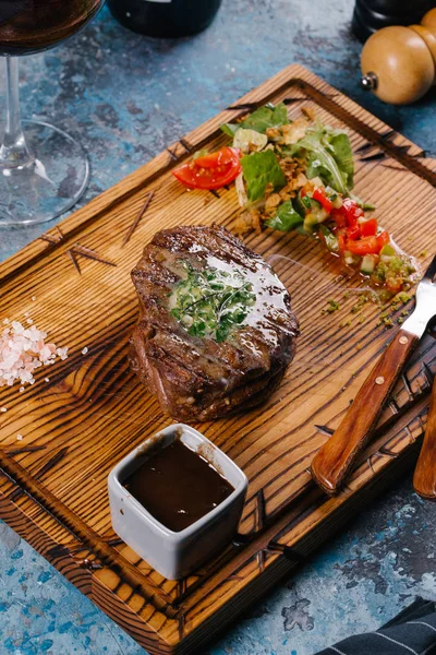 Taze orta çiğ biftek Ahşap Doğrama tahtası üzerinde sebze salatası ile servis