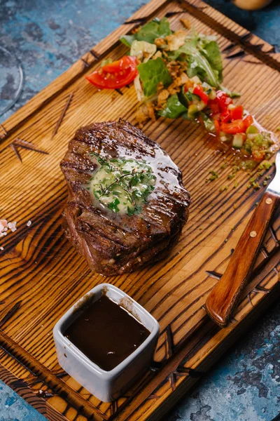 Taze orta çiğ biftek Ahşap Doğrama tahtası üzerinde sebze salatası ile servis