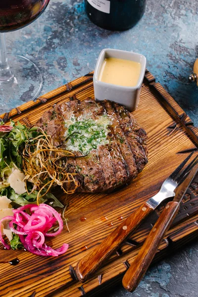 Grilled patty cake served with arugula salad and cheese on wooden board