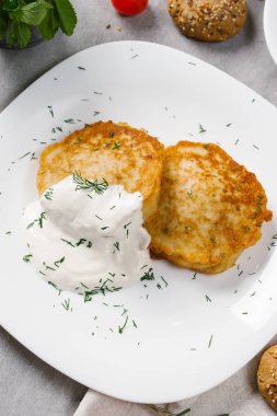 Ekşi krema ve dereotu beyaz plaka üzerinde patates pancakes