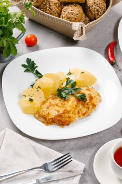 Beyaz tabakta haşlanmış patates ile taze hamburger biftek servis