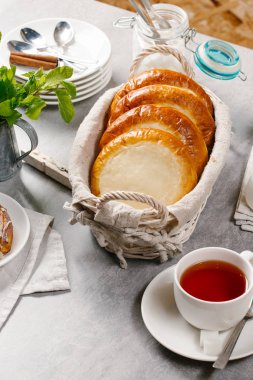 Hasır sepet fincan çay ile servis içinde süzme peynir ile taze pişmiş çörekler
