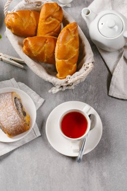 Hasır sepet gri taş zemin üzerine çay ile servis içinde taze pişmiş çörekler