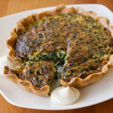 Beyaz plaka üzerinde beyaz sos ile servis taze pişmiş ıspanak quiche 