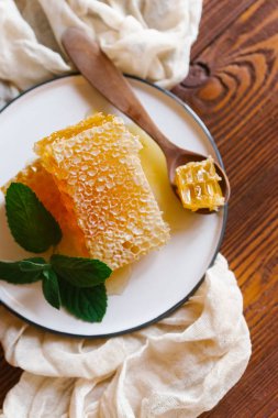 Bej keten kumaş nane dal beyaz plaka üzerinde tahta kaşıkla üstten görünüm taze peteğin süslenmiş