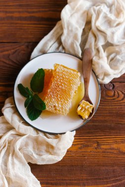 Bej keten kumaş nane dal beyaz plaka üzerinde tahta kaşıkla üstten görünüm taze peteğin süslenmiş