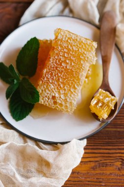 Bej keten kumaş nane dal beyaz plaka üzerinde tahta kaşıkla üstten görünüm taze peteğin süslenmiş