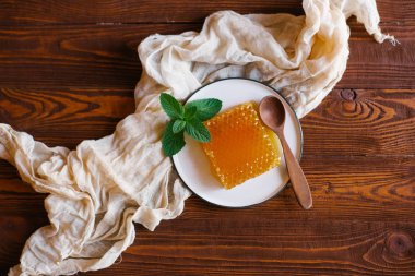 Taze peteğin süslenmiş beyaz plaka üzerinde taze nane dal üzerinde bej keten kumaş üstten görünüm