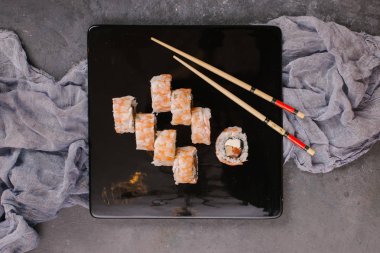 Üstten görünüm taze geleneksel Japon ile chopsticks beton zemin üzerine siyah plaka üzerinde rulo