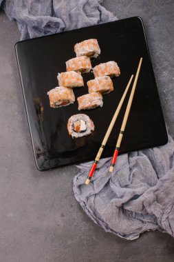 Üstten görünüm taze geleneksel Japon ile chopsticks beton zemin üzerine siyah plaka üzerinde rulo