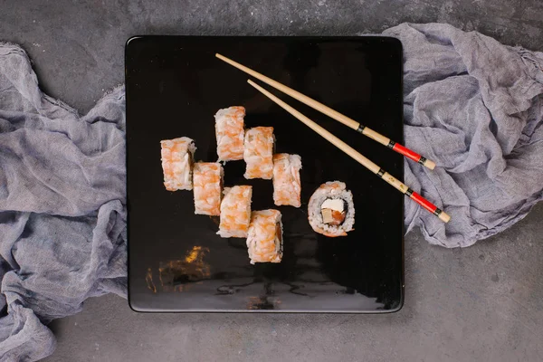 Üstten görünüm taze geleneksel Japon ile chopsticks beton zemin üzerine siyah plaka üzerinde rulo