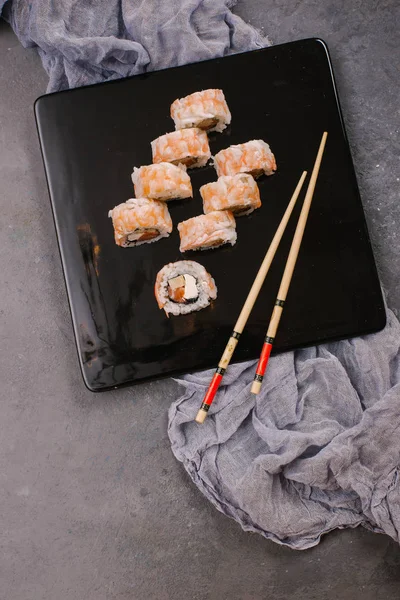Üstten görünüm taze geleneksel Japon ile chopsticks beton zemin üzerine siyah plaka üzerinde rulo